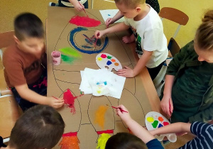 Chłopcy malują farbami rakietę.